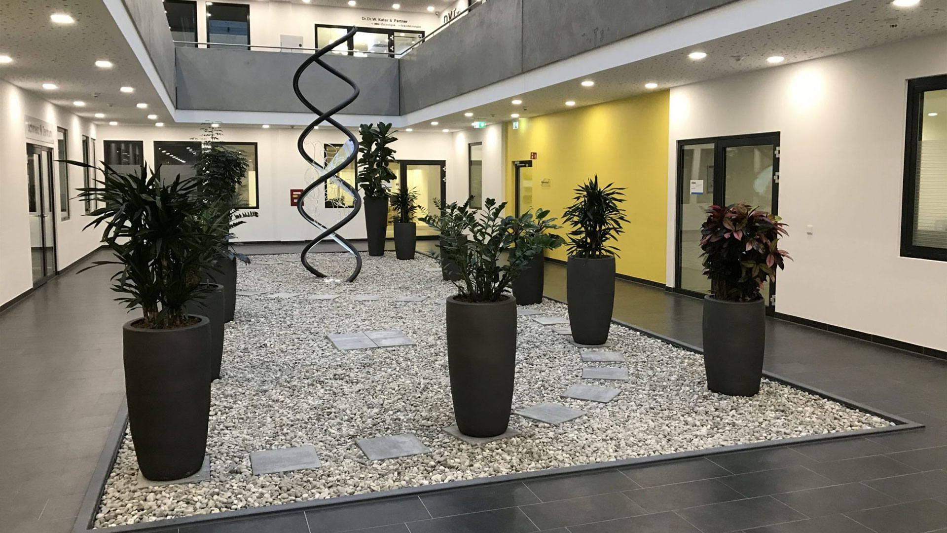 Modernes Innenatrium mit Skulptur und Bepflanzung im Gesundheitscampus Bad Homburg
